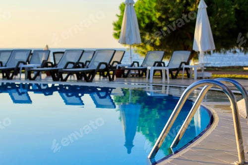 Preview: Tropical empty pool view with a steel ladder to enter the water. Social distancing, coronavirus.