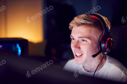 Preview: Teenage Boy Wearing Headset Gaming At Home Using Dual Computer Screens