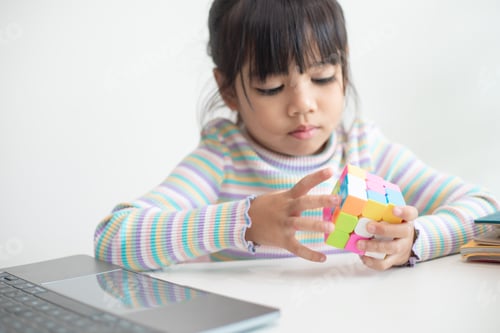 Preview: Asian little cute girl holding Rubik's cube in her hands. Rubik's cube is a game that increases the
