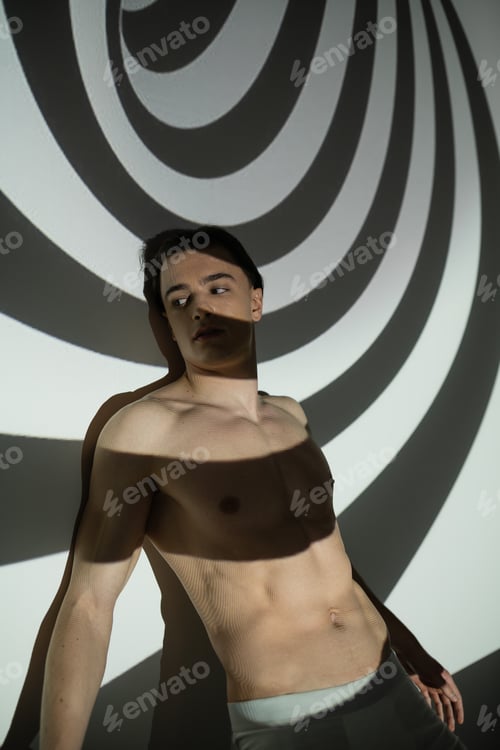 Preview: sexy, young and good looking man with muscular torso and shirtless body looking away while standing