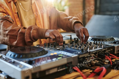 Preview: Hands of black man regulating sounds on dj set while turning mixers
