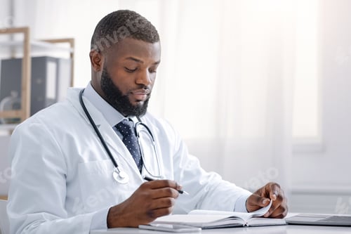 Preview: Busy black doctor taking notes, sitting at workdesk