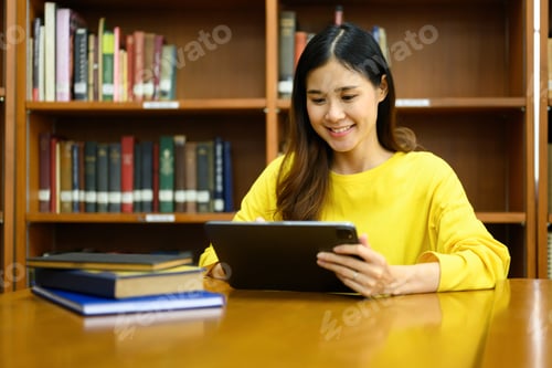 Preview: Smiling female college students searching information on digital tablet in library.