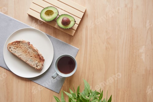 Preview: minimalist breakfast table with a cup of coffee, toast on a plate and avocado cut in half.