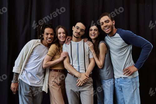 Preview: group photo of cheerful interracial colleagues looking at camera near black drape in office