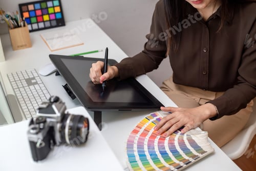 Preview: Business woman holding pen working using tablet and color samples at office.