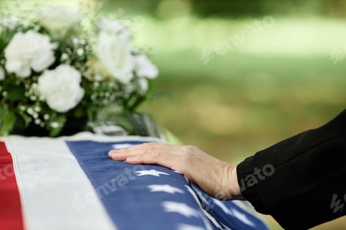 Preview: Male hand on coffin covered with American flag