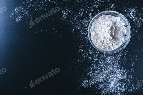 Preview: white flour sprinkled on a dark wooden table. top view