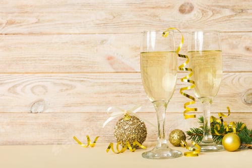 Preview: Champagne glasses and christmas decor on colored holiday background. Flat lay New Year decorations