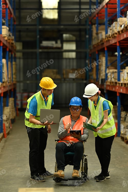 Preview: Two young storehouse worker and male manager in wheelchair working on a digital tablet.