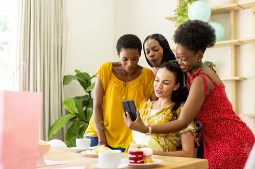 Preview: Friends gathering around smartphone, sharing joyful moments at home with desserts
