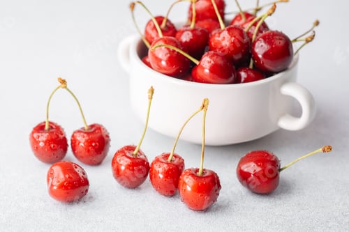 Preview: Cherries scattered and in bowl on white for snack prep or bright food styling concept