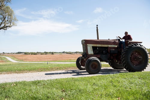 Preview: Farmer driving tractor on rural road, Missouri, USA