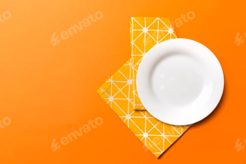 Preview: Top view on colored background empty round white plate on tablecloth for food.