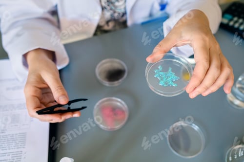 Preview: Unrecognizable female scientist showing blue glitter in facial cream sample over petri dish on lab