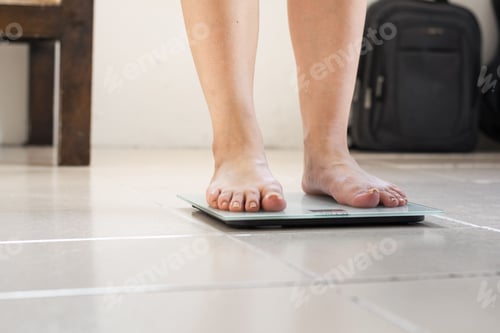 Preview: Feet of a Latina woman with one foot placed on the scale