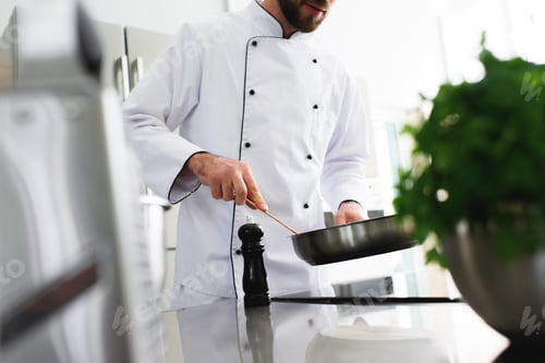 Preview: cropped image of chef frying food on frying pan at restaurant kitchen