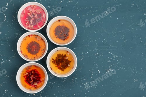 Preview: Tea concept. Different kinds of dry tea in ceramic bowls and cups of aromatic tea
