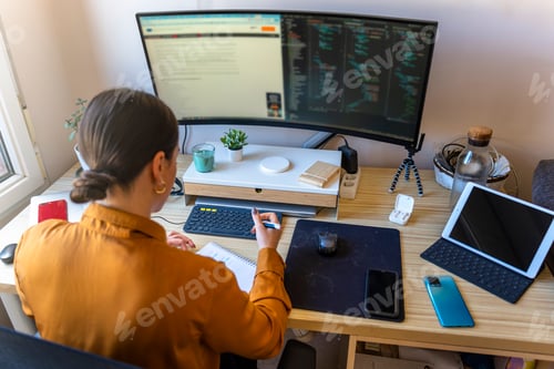 Preview: Computer programmer working from home. Teleworking concept. Business woman taking notes.