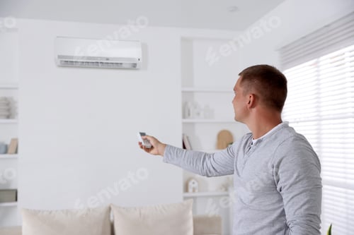 Preview: Man using remote to control air conditioner at home