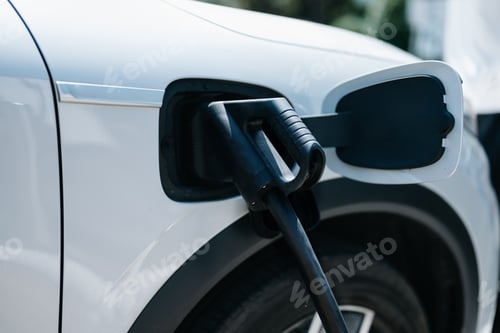 Preview: Hand plugging in a charger in an electric car socket.Electric car or ev is charging at station