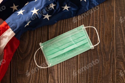 Visualização: Acima da bandeira dos EUA e proteção facial para coronavírus em uma placa de fundo de madeira velha marrom