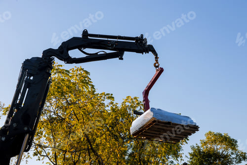 Preview: A crane lifting and moving pallet materials to home building roof