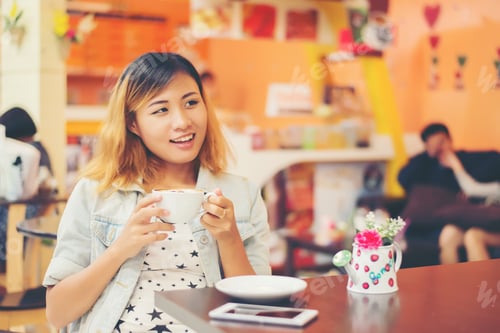 Preview: Portrait of young beautiful woman sitting in a cafe holding hot coffee.