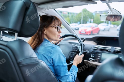 Preview: Middle-aged woman driver sitting behind wheel in car