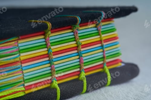 Preview: Closeup shot of a book with colorful paper bound with woven thread