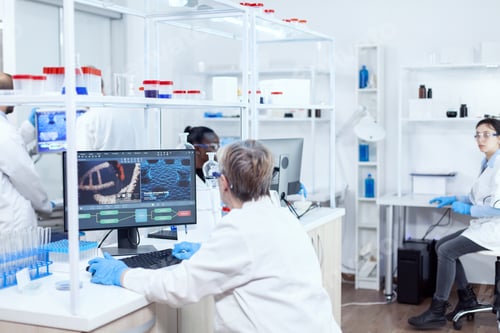 Preview: Elderly virologist working on computer with virus on display