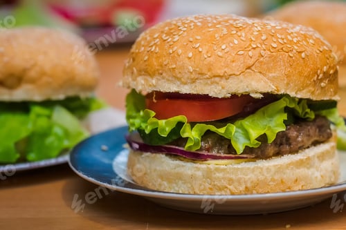 Preview: Two Homemade burger with tomato and beef patty, fresh toppings on whole grain artisan bun on kitchen