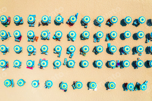 Preview: Aerial view of colorful blue umbrellas on sandy beach at sunset