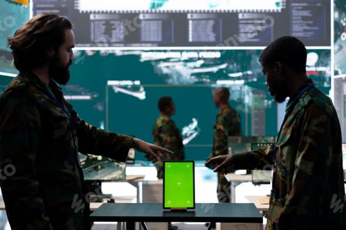 Preview: Diverse team of soldiers examine information on a green screen