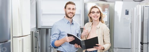 Preview: panoramic shot of smiling consultant holding folder and woman showing like in home appliance store