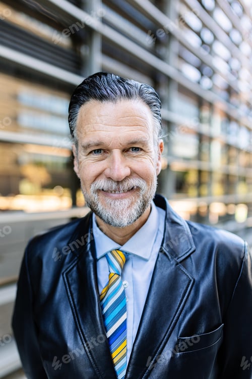 Preview: Vertical portrait of senior businessman looking at camera over office building
