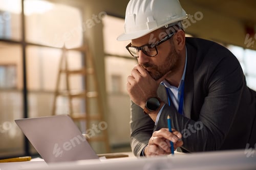 Preview: Pensive architect working on laptop at construction site.