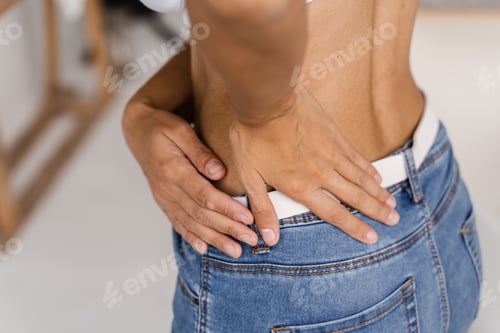 Preview: Woman Holding Lower Back in Pain Indoors