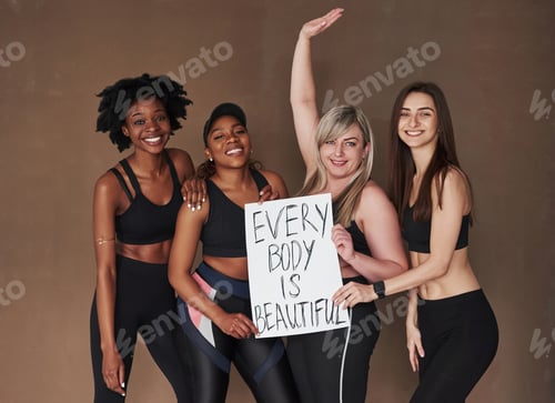 Preview: No complexes. Group of multi ethnic women standing in the studio against brown background