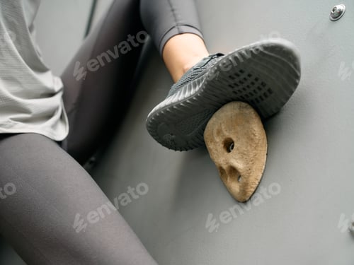 Preview: Close up of climber s foot on rock climbing hold against a grey background