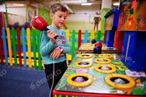 Preview: Boy play in hit the hamster game machine at indoor playground.