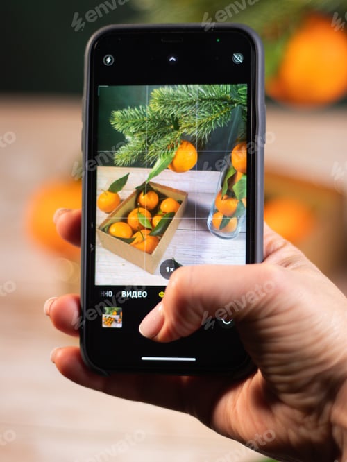 Preview: hand with phone taking pictures of tangerines