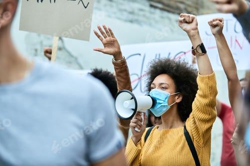 Preview: Crowd of people with protective face masks protesting during coronavirus pandemic.