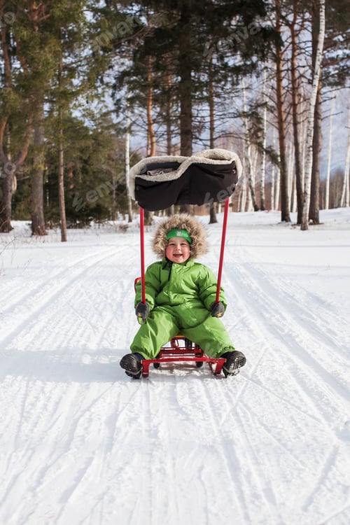 Preview: Happy child sledding in winter forest snowy day. Concept of winter