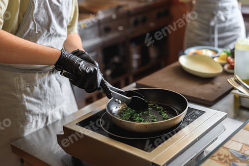 Preview: Close up of kitchen worker is frying greens for cooking main dish in restaurant
