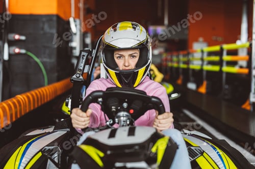 Preview: female driver looking at camera defiantly with her racing helmet holding the steering wheel