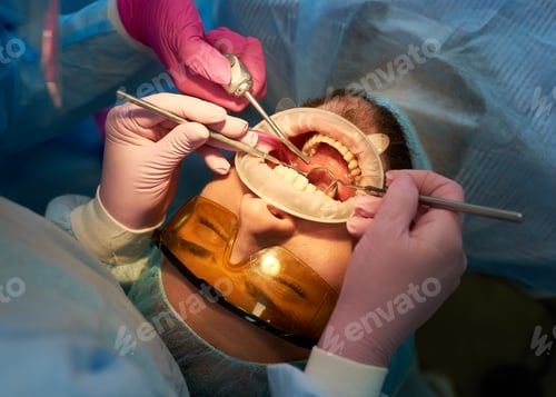 Preview: Male client with orange dental glasses is having his teeth checked and attended