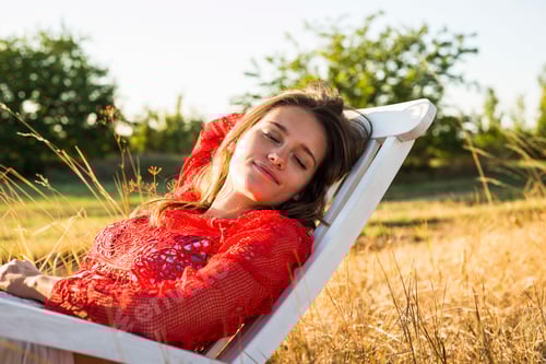 Preview: Portrait of woman relaxing on a deck chair on a meadow