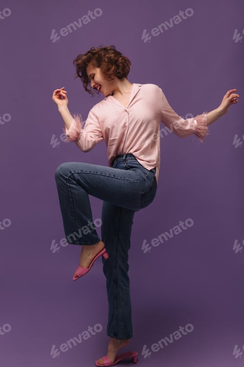 Preview: Stylish lady dancing at studio against violet background. Attractive young girl with short curly ha