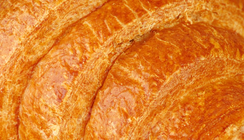 Preview: Extreme close up of crispy croissant texture. Macro shot of golden brown flaky puff pastry surface.